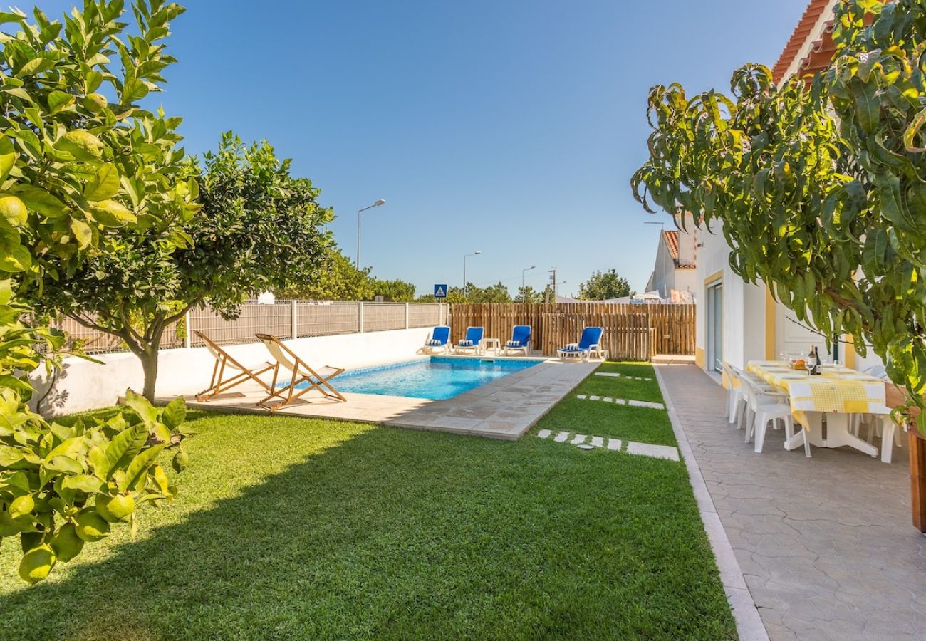 Piscina rodeada de um jardim e espaço de refeições.     