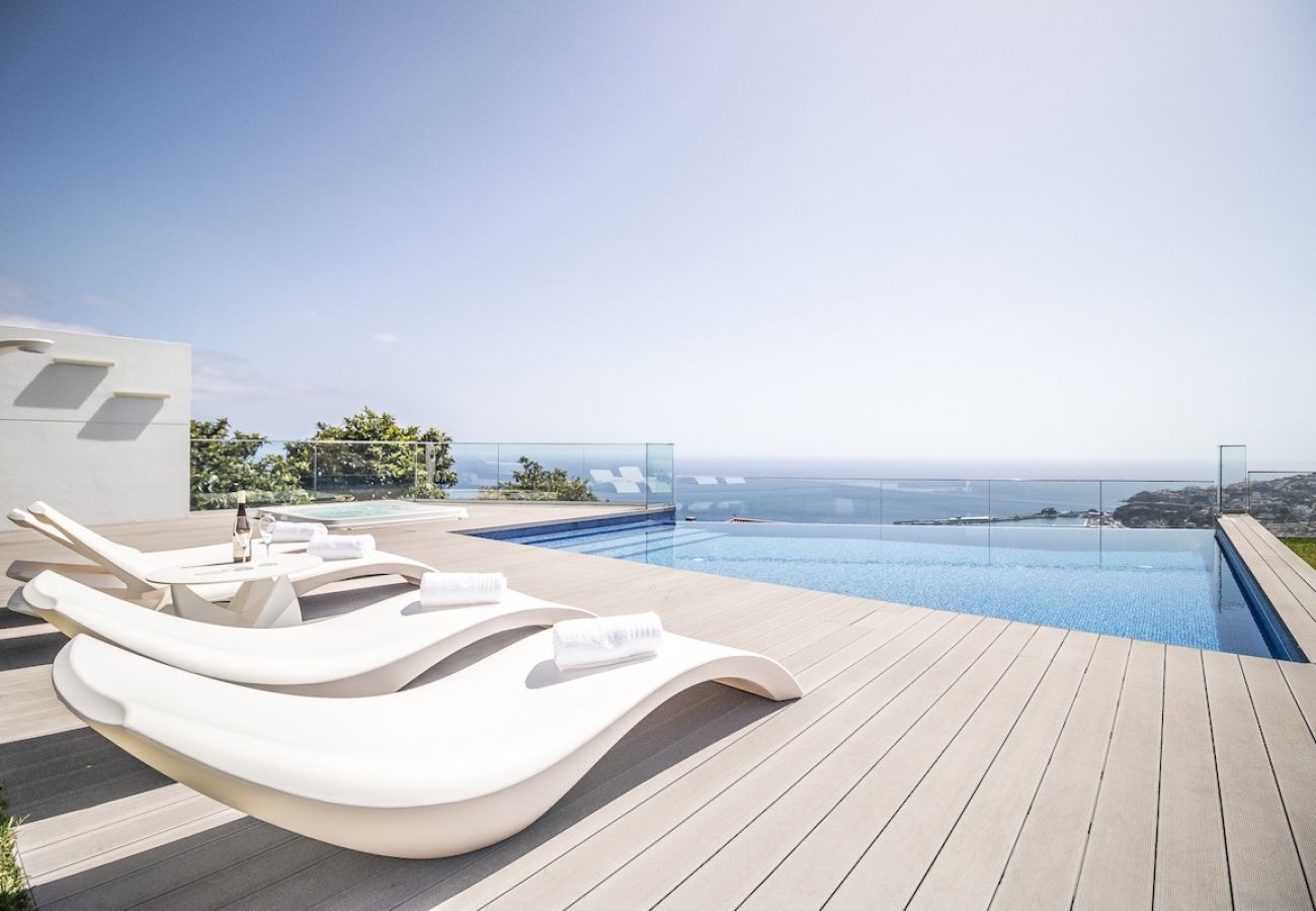 Piscina rodeada por um jardim com vista panorâmica para o mar.